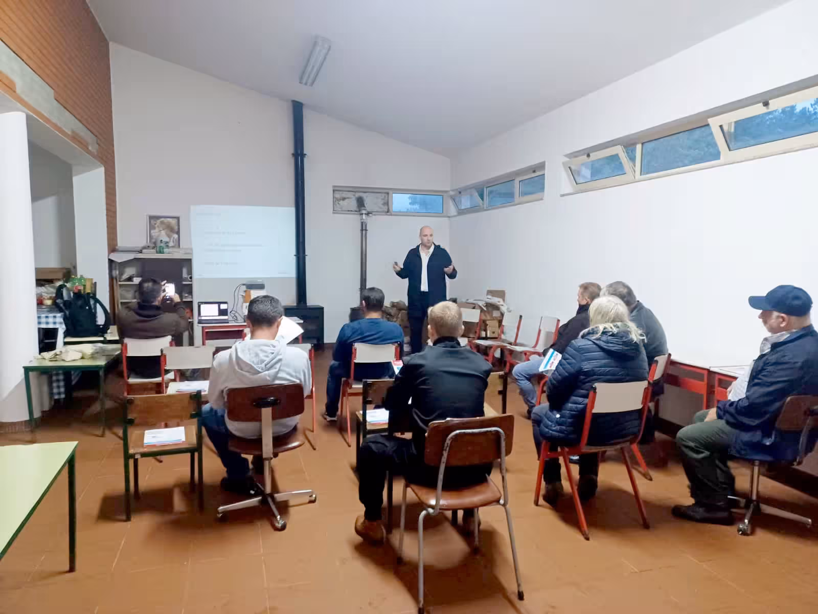 A community session under way in a village hall, residents seated facing the facilitator