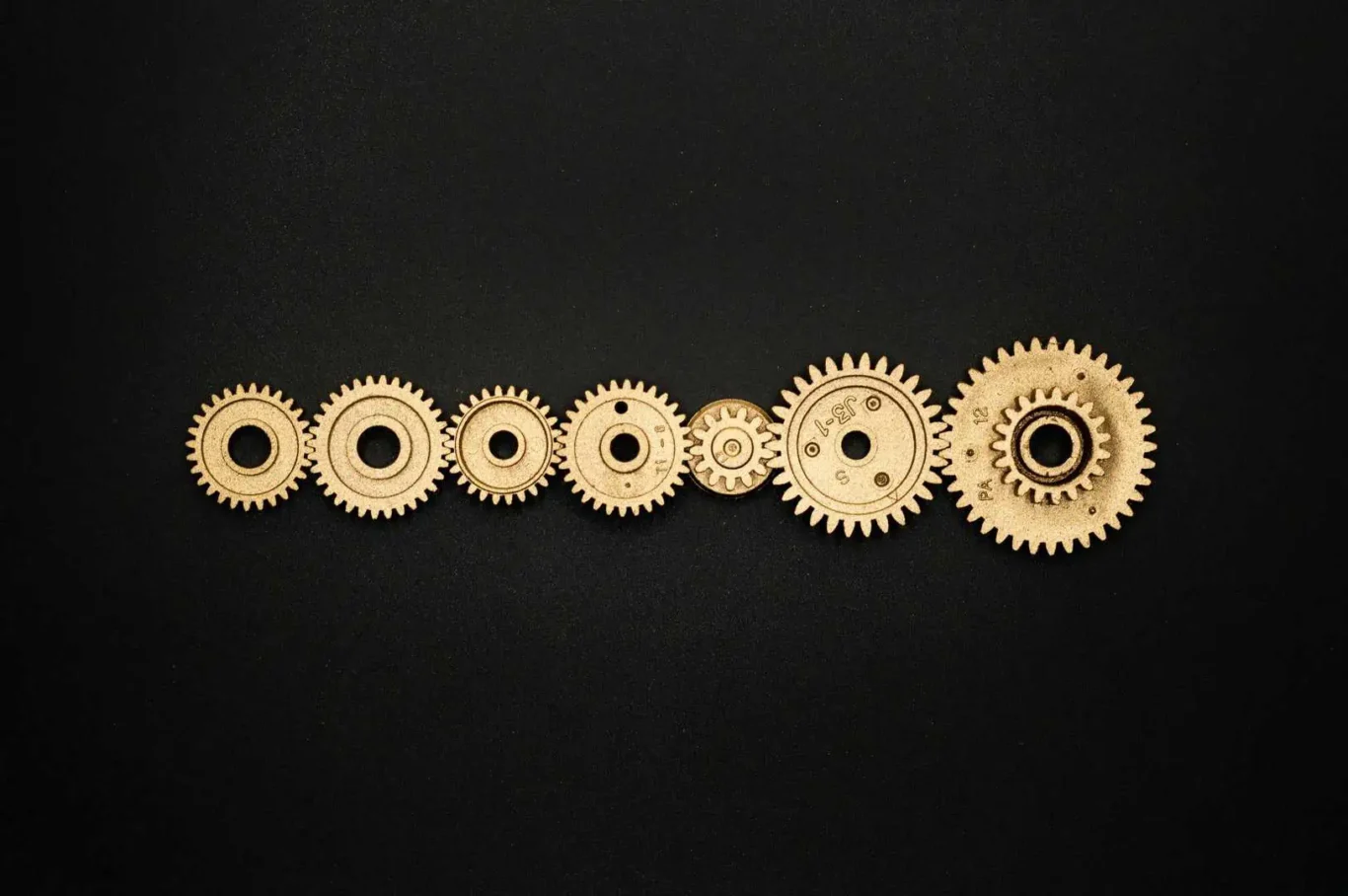 A line of gold gears of different sizes are set against a black background