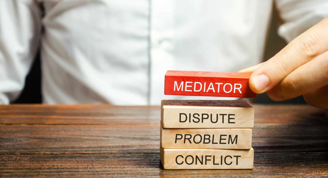 A man holds wooden blocks with the word Mediator, dispute, problem, conflict