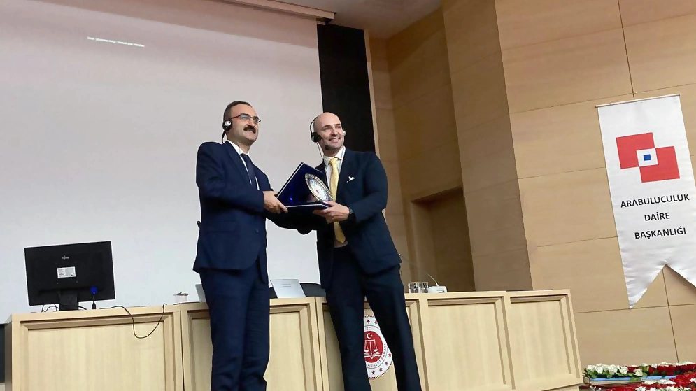 Thomas Gaultier receives an award on the stage of a big conference room.